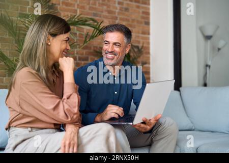 Two happy professional business people talking using laptop in office. Stock Photo