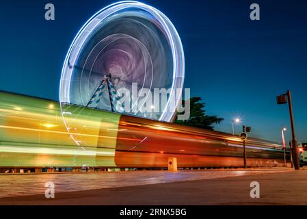 Feeris wheel and tram traces of light in evening lights in Tours city, France Stock Photo
