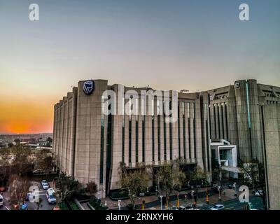 Beautiful and tall Standard bank buildings in Simmonds street Selby Johannesburg CBD area under a cloudy and sunset sky Stock Photo