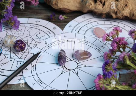 Zodiac wheels, gemstones, flowers and astrology dices on wooden table, closeup Stock Photo