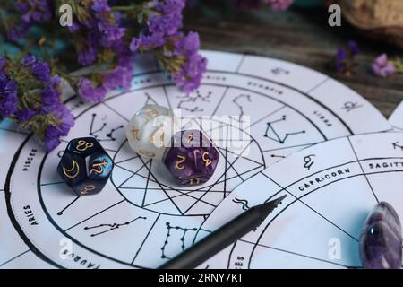 Zodiac wheels, flowers and astrology dices on wooden table, closeup Stock Photo