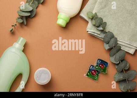 Flat lay composition with bottles of fabric softener and laundry detergent pods on brown background, space for text Stock Photo