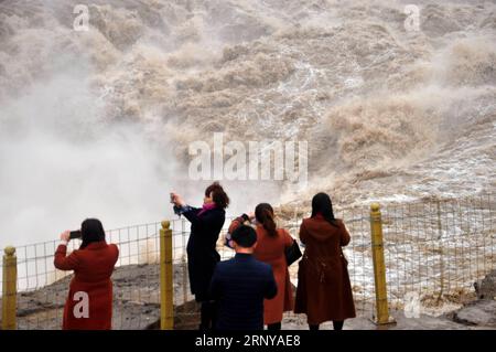 (180307) -- LINFEN, March 7, 2018 -- Tourists take photos of the Hukou Waterfall of the Yellow River in Jixian County, north China s Shanxi Province, March 6, 2018. As temperature rises and ice melts on the upper reaches of the Yellow River, the water volume at Hukou Waterfall surges. )(wsw) CHINA-SHANXI-HUKOU WATERFALL (CN) LyuxGuiming PUBLICATIONxNOTxINxCHN Stock Photo