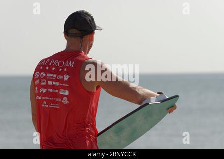 Male contestant waits for the next wave at the Zap Pro/Am Championships of Skimboarding, August 11, 2023, Dewey Beach, Delaware USA. Stock Photo