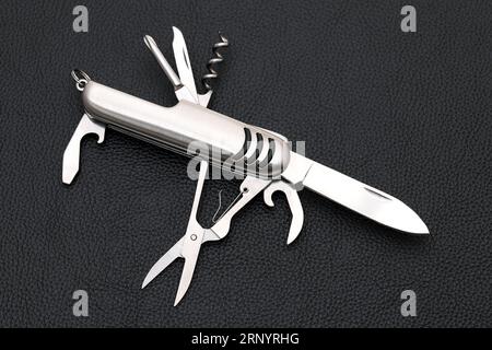 Close up photo of swiss army knife on black leather background Stock Photo