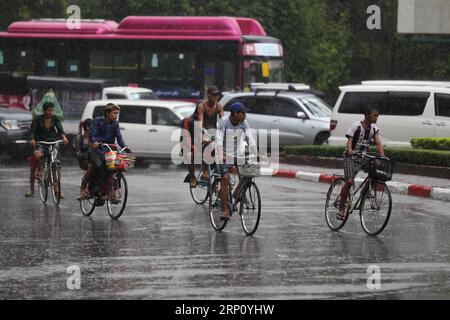 (180530) -- YANGON, May 30, 2018 -- People ride bicycles in the rain in Yangon, Myanmar, May 30, 2018. Strong wind, coupled with torrential rain, has destroyed over 500 houses in Shwe Pyi Tha township, Myanmar s Yangon region, the official Global New Light of Myanmar reported Wednesday. ) (hy) MYANMAR-YANGON-MONSOON-RAINING UxAung PUBLICATIONxNOTxINxCHN Stock Photo