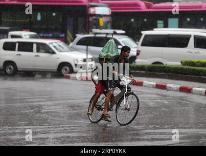 (180530) -- YANGON, May 30, 2018 -- Boys ride bicycle in the rain in Yangon, Myanmar, May 30, 2018. Strong wind, coupled with torrential rain, has destroyed over 500 houses in Shwe Pyi Tha township, Myanmar s Yangon region, the official Global New Light of Myanmar reported Wednesday. ) (hy) MYANMAR-YANGON-MONSOON-RAINING UxAung PUBLICATIONxNOTxINxCHN Stock Photo
