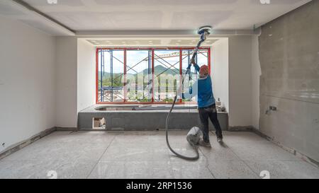 Laborer performing and polishing sand and cement screed wall on the construction site Stock Photo