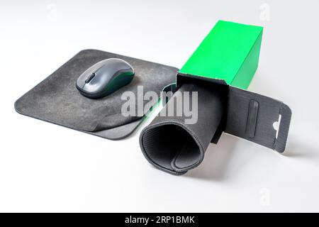 Open retail box with a brand new computer mouse pad placed by a well-used one set on a white table. Stock Photo