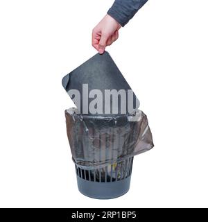 Close-up view of a hand tossing a worn and well-used mouse pad into a trash bin. Stock Photo