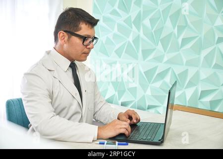 Doctor using laptop sitting on a office Stock Photo
