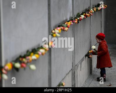 (180706) -- BERLIN, July 6, 2018 -- A girl puts flowers onto a part of the former Berlin Wall during a memorial activity to commemorate the 25th anniversary of the fall of the Berlin Wall in Berlin, Germany, on Nov. 9, 2014. ) (wtc) GERMANY-BERLIN-DAILY LIFE ZhangxFan PUBLICATIONxNOTxINxCHN Stock Photo