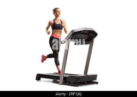 Young woman in leggings and crop top running on a treadmill isolated on white background Stock Photo