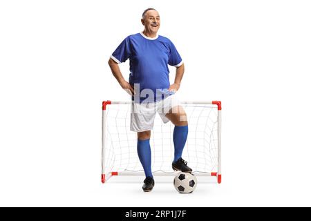Smiling mature man wearing a football sports jersey and standing in front of a mini goal isolated on white background Stock Photo