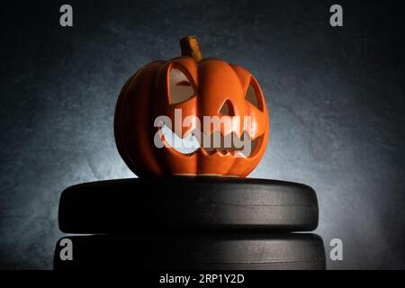 Halloween pumpkin decoration and dumbbell barbell weight plates. Healthy fitness autumn fall spooky composition. Gym workout, sport training concept. Stock Photo