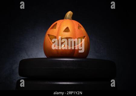 Halloween pumpkin decoration and dumbbell barbell weight plates. Healthy fitness autumn fall spooky composition. Gym workout, sport training concept. Stock Photo