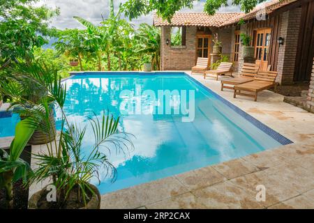 Beautiful swimming pool surrounded by nature. A crystal clear swimming pool surrounded by trees. Concept of home pool designs Stock Photo