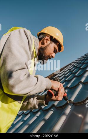 Man working roof with drill low view Stock Photo