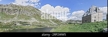 Photo with reduced dynamics saturation HDR of view on left mountain lake right historical hotel accommodation Ospizio San Gottardo Sankt Gotthard Stock Photo