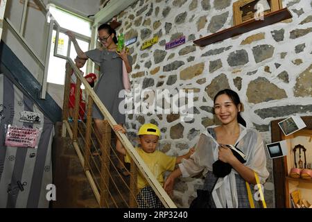 (180917) -- PINGTAN, Sept. 17, 2018 -- Tourists visit the art zone of Rocks Can Sing in Beigang Village of Pingtan County, southeast China s Fujian Province, Sept. 7, 2018. When tourists get close to Rocks Can Sing, they may see artists playing music with the rocks, and people sipping coffee in rock houses. Rocks Can Sing is an art project which takes in accommodation, live music, restaurant, cafe and souvenir store. Now, a total of 10 young people from the mainland and Taiwan, including Taiwanese Lin I Chen and her boyfriend Liao Che Wei, work for the art project to promote cultural and touri Stock Photo