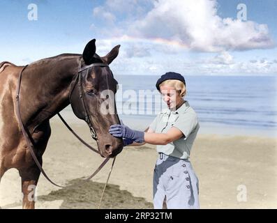 Woman, possibly a fashion model, with a horse on the beach of Scheveningen, The Netherlands. Photographer: Willem van de Poll. Date: Unknown. Sky has Stock Photo
