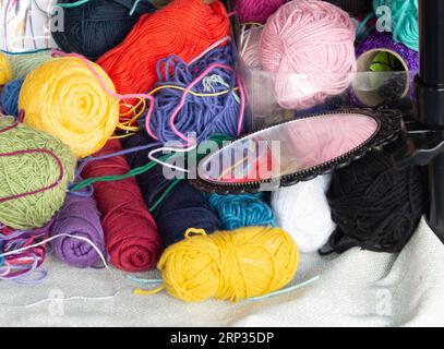 Multicolored wool balls and a small mirror on a craftsman's stand. Shot in horizontal. Stock Photo