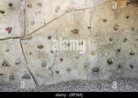 A rock wall in a park with holds for climbing Stock Photo