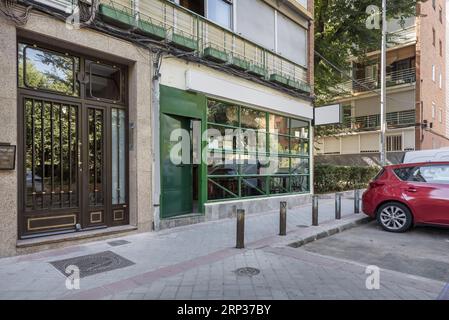 Image of a commercial premises at street level with a glass and iron enclosure painted green on a humble street in the city Stock Photo