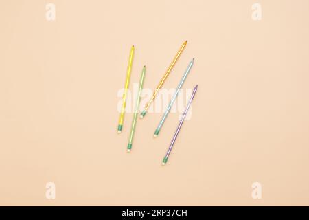 A few assorted colored graphite lead pencils with small erasers on one end on a smooth, soft pink surface Stock Photo