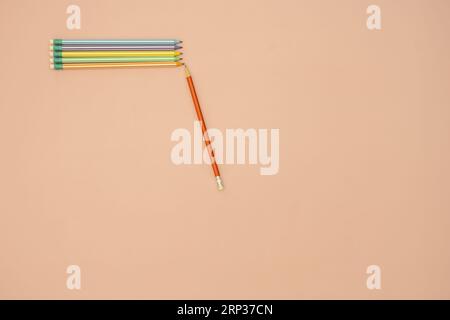 A few assorted colored graphite pencils with small erasers on one end in the corner of a smooth, soft pink surface Stock Photo