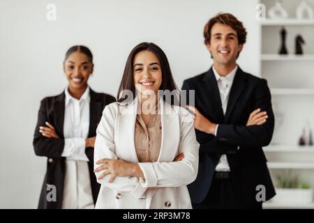 Leadership concept. Businesswoman posing in office interior with her multiracial business team and smiling at camera Stock Photo
