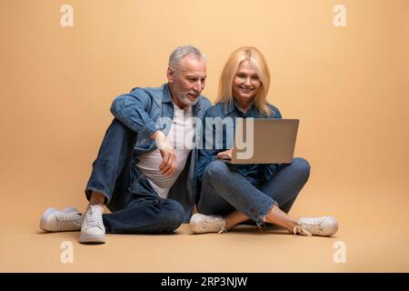 Retired man and woman friends using laptop, watching movie Stock Photo