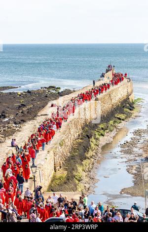 St Andrews, Fife, Scotland. 03 September 2023. New students at the University of St Andrews wearing red robes take part in the traditional Pier Walk along the harbour walls of St Andrews before the start of the new academic year. The Martinmas Semester © Richard Newton / Alamy Live News Stock Photo