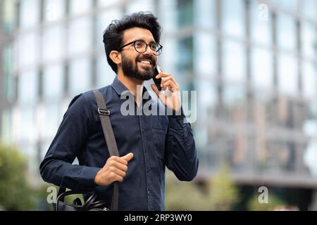 Indian entrepreneur walking by street and talking on phone Stock Photo