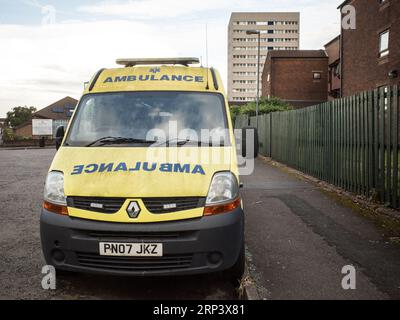 A vandalised ambulance is abandoned in a run down housing estate in the outskirts of Birmingham, tower block in background, England, UK 2023. Stock Photo