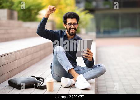 Excited young indian man using digital tablet on the street Stock Photo