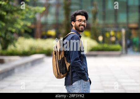 Cool young hindu guy with backpack walking by street Stock Photo