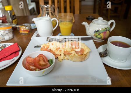 full English breakfast served with Scrambled eggs with salmon , tea and orange juice on a table. England  UK Stock Photo