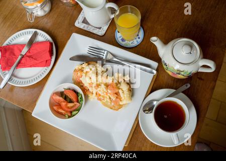 full English breakfast served with Scrambled eggs with salmon , tea and orange juice on a table. England  UK Stock Photo
