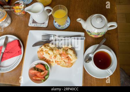 full English breakfast served with Scrambled eggs with salmon , tea and orange juice on a table. England  UK Stock Photo