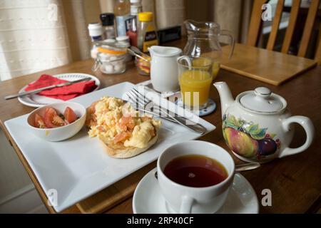 full English breakfast served with Scrambled eggs with salmon , tea and orange juice on a table. England  UK Stock Photo