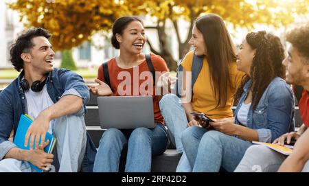 Diverse multiethnic students sitting on stairs outdoors in university campus Stock Photo
