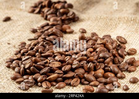 Heap of roasted coffee beans on burlap background close-up. Stock Photo
