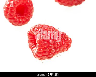 Three ripe raspberries close-up on a white background. Stock Photo