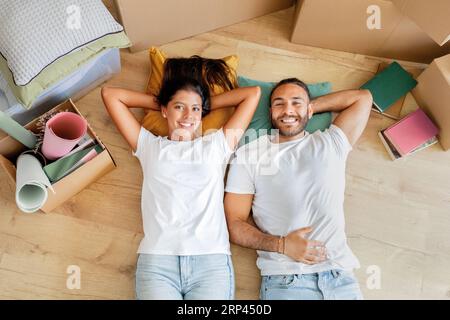 Relaxed happy couple lying on floor in empty apartment Stock Photo
