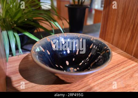 (181031) -- JIANYANG, Oct. 31, 2018 -- Photo taken on Oct. 29, 2018 shows Jian Zhan , a kind of black glaze bowl, at an exhibition hall in Jianyang, southeast China s Fujiang Province. Jian Zhan , a kind of temmoku glaze or black glaze porcelain, was then used only by emperors of ancient China s Song Dynasty (960-1279). Famous for its nobility and gorgeousness, Jian Zhan was numerously exported overseas through the Silk Road on the sea. However, after Song Dynasty, those traditional firing techniques to make Jian Zhan failed to be handed down to future generations. In recent years, those ancie Stock Photo