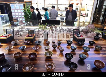(181031) -- JIANYANG, Oct. 31, 2018 -- Tourists view Jian Zhan , a kind of black glaze bowl, at an exhibition hall in Jianyang, southeast China s Fujiang Province, Oct. 29, 2018. Jian Zhan , a kind of temmoku glaze or black glaze porcelain, was then used only by emperors of ancient China s Song Dynasty (960-1279). Famous for its nobility and gorgeousness, Jian Zhan was numerously exported overseas through the Silk Road on the sea. However, after Song Dynasty, those traditional firing techniques to make Jian Zhan failed to be handed down to future generations. In recent years, those ancient tec Stock Photo