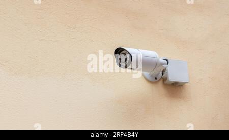 Security Camera CCTV system on beige empty wall background. Modern technology, life and estate protection. Ad template, copy space Stock Photo