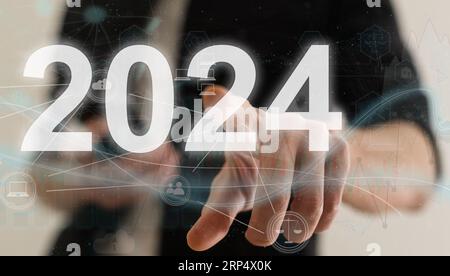 Businesswoman pointing at figure 2024 among others ones on grey background Stock Photo
