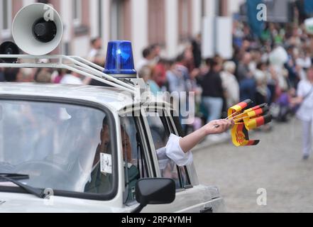 Aue Bad Schlema, Germany. 03rd Sep, 2023. Participants in the parade at the Day of the Saxons hold flags of the former GDR from a police car from GDR times. Saxony's largest folk and local festival traditionally takes place on the first weekend in September. Credit: Sebastian Willnow/dpa/Alamy Live News Stock Photo